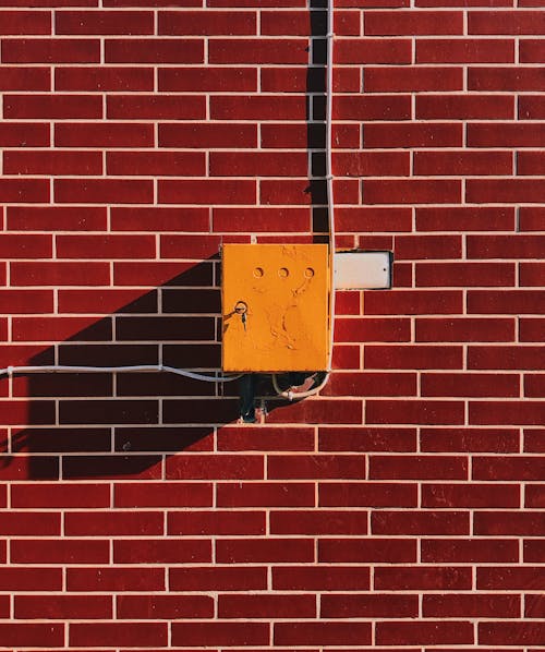 Boîte électrique Jaune Sur Mur De Briques Marron