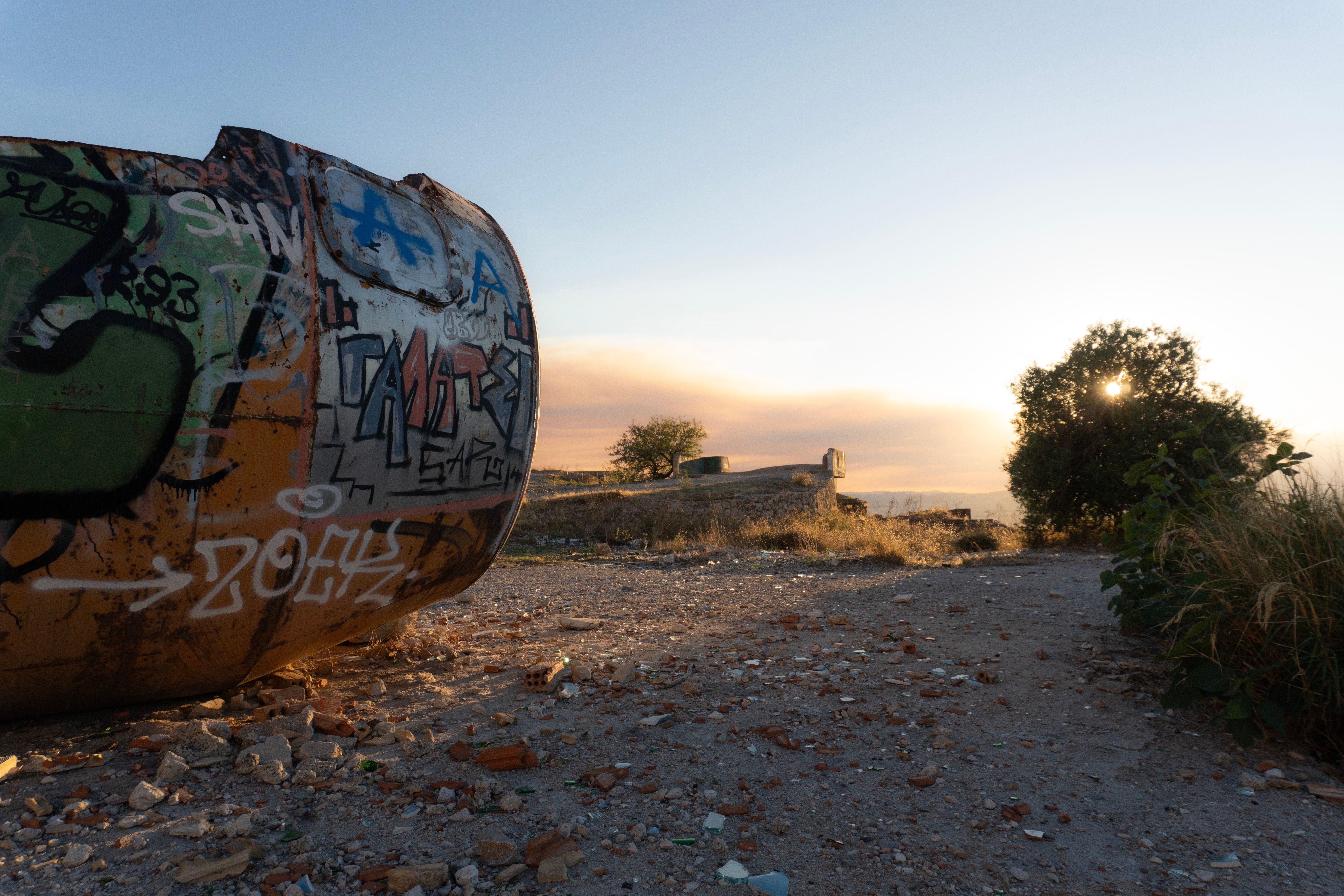 Graffiti on Rusty Barrel at Sunset in Athens · Free Stock Photo