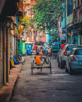 A vibrant street in Kolkata bustling with rickshaws and parked vehicles, showcasing local life.