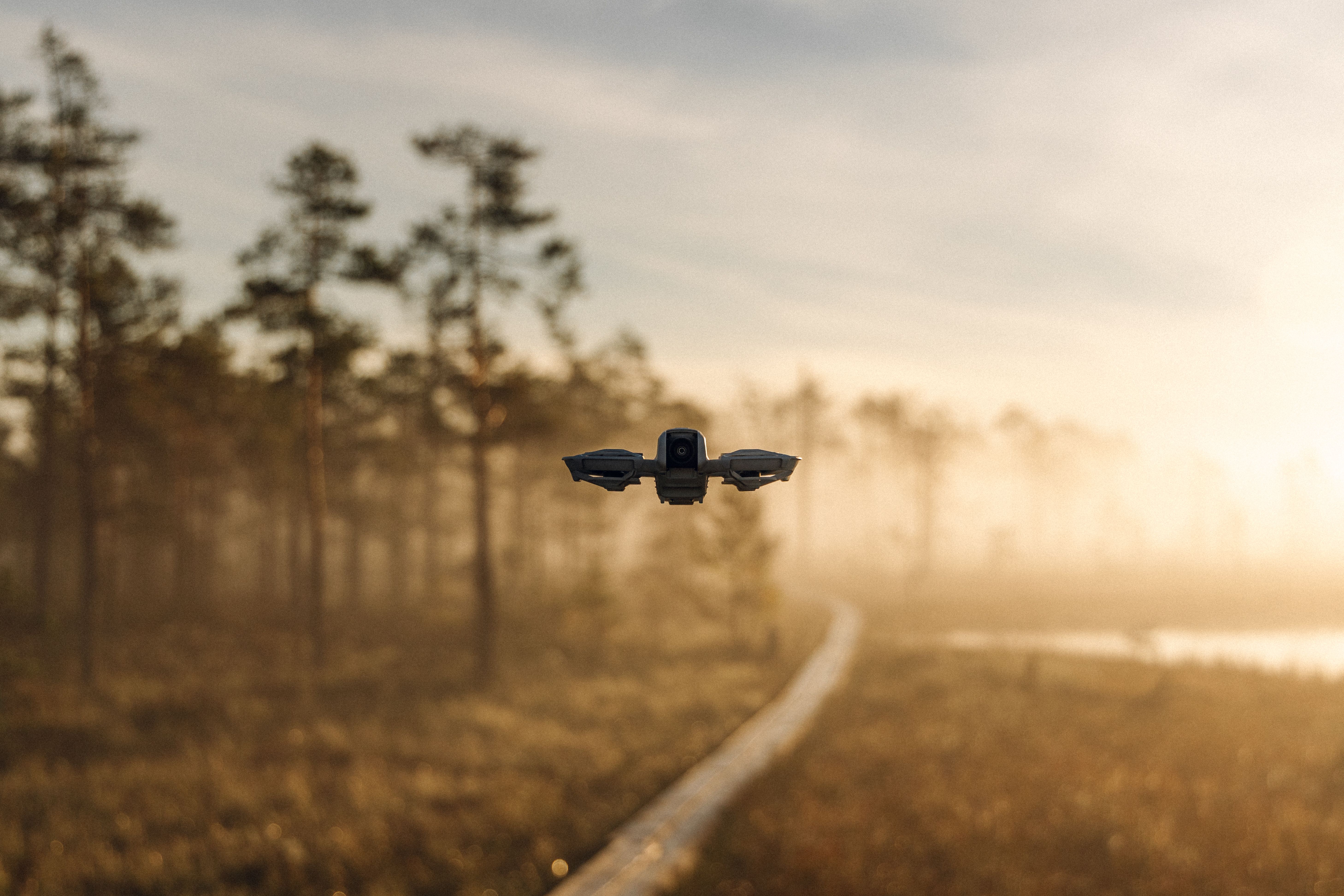 Drone hovering over a misty forest path at sunrise