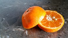 一个新鲜切开的橙子在大理石表面露出多汁的果肉，充满活力