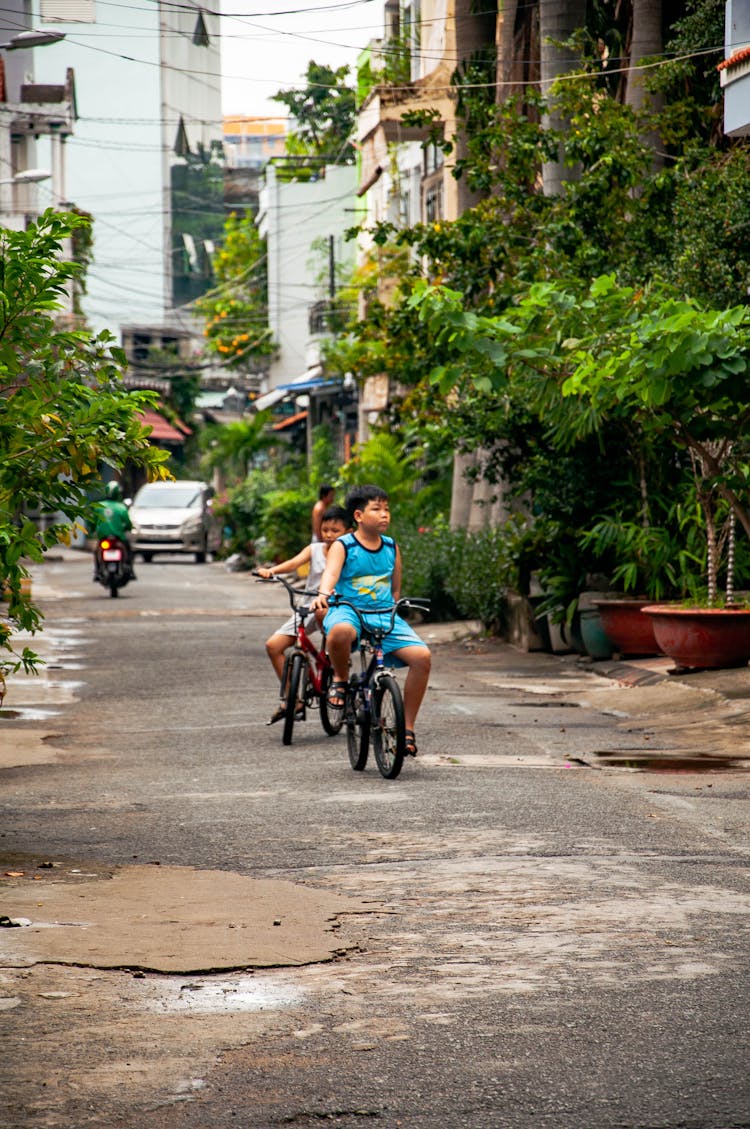 Photo Of Two Boys  Riding Bikes On The Street