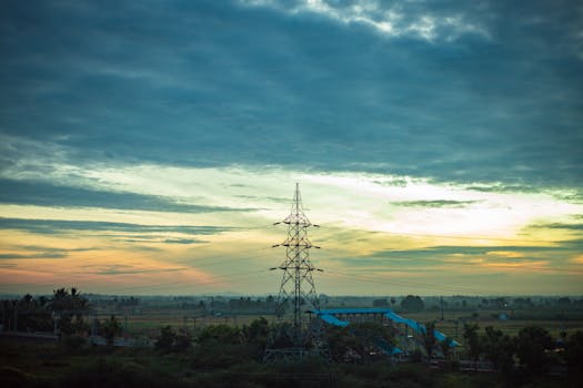 A stunning sunrise view over rural fields in Nanguneri, India with an electric tower.