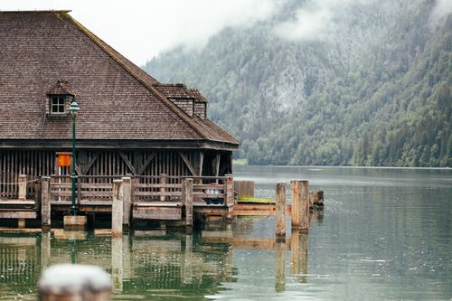 Free Scenic view of a wooden boat house on Lake Königsee surrounded by lush mountains. Stock Photo