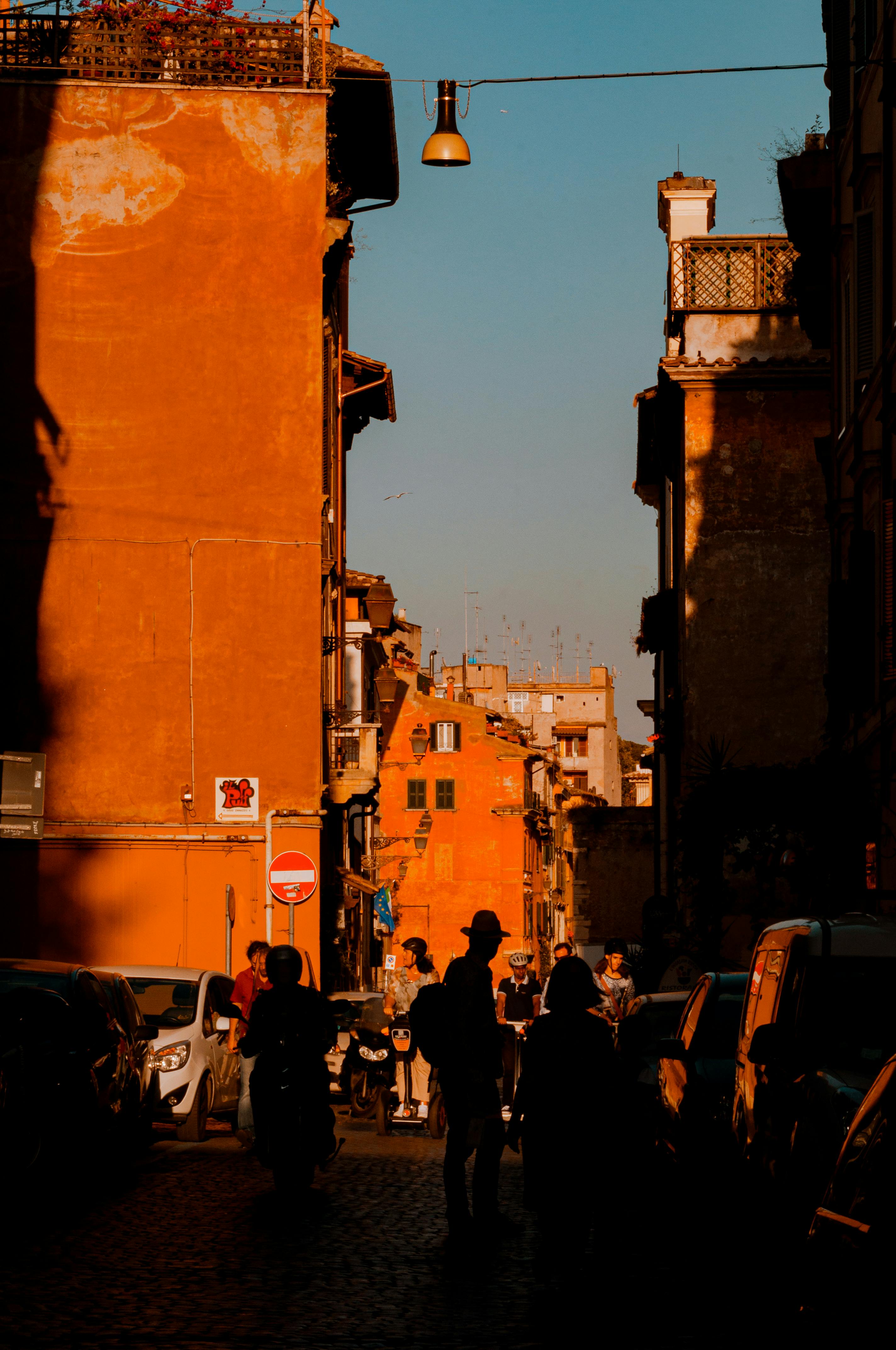 Bustling street in Rome's ancient architecture with evening light casting shadows.