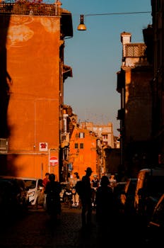 Bustling street in Rome's ancient architecture with evening light casting shadows.