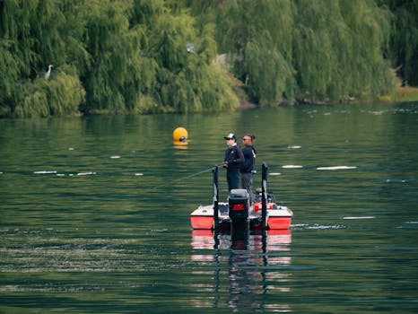 Two people fishing from a boat on a serene lake with lush greenery.