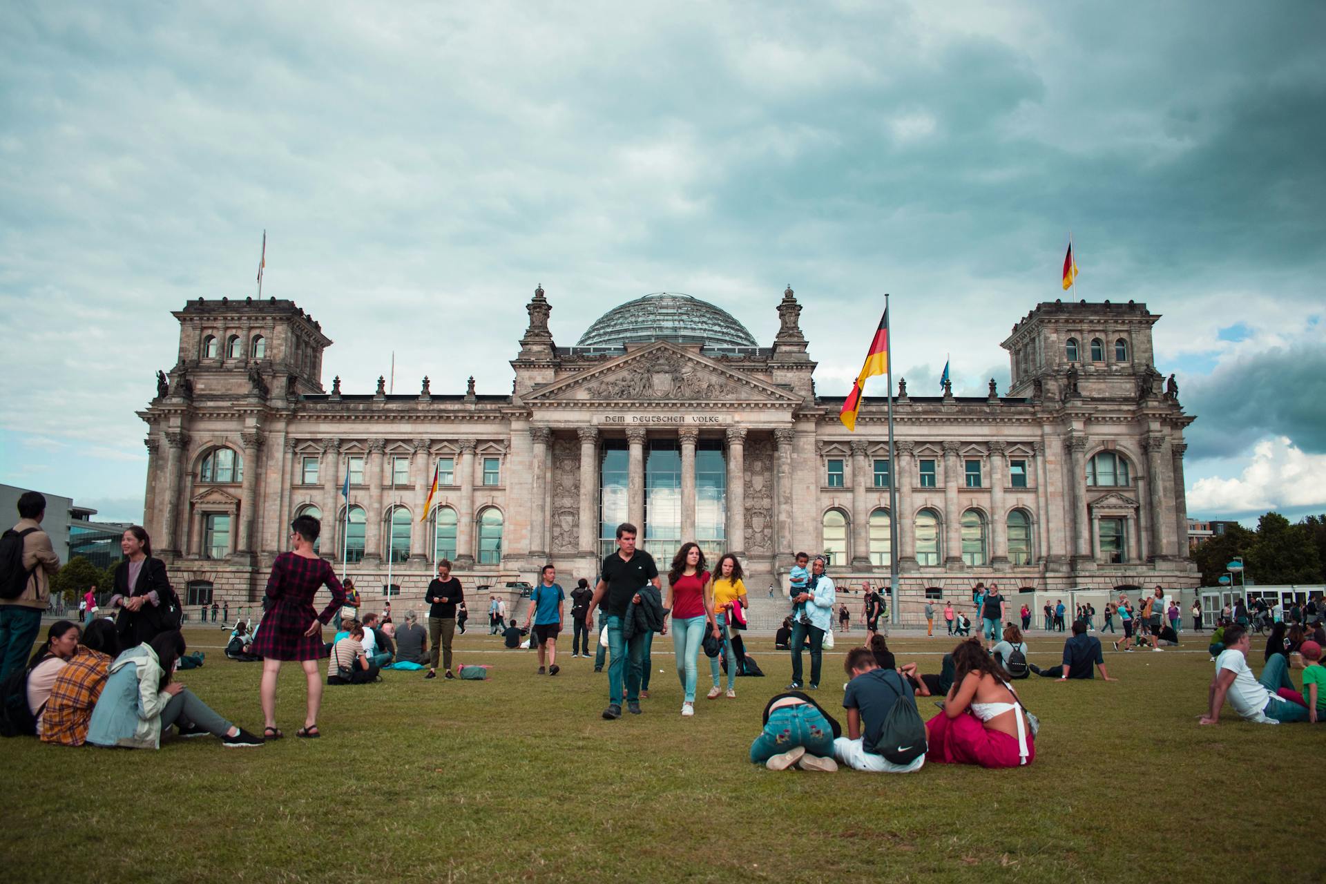 Tourists relaxing on the lawn in front of the historic Reichstag Building in Berlin, Germany during a summer day.