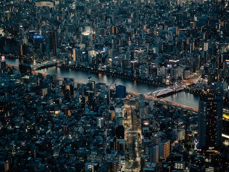 Stunning aerial shot of Tokyo cityscape at night featuring illuminated buildings and river.