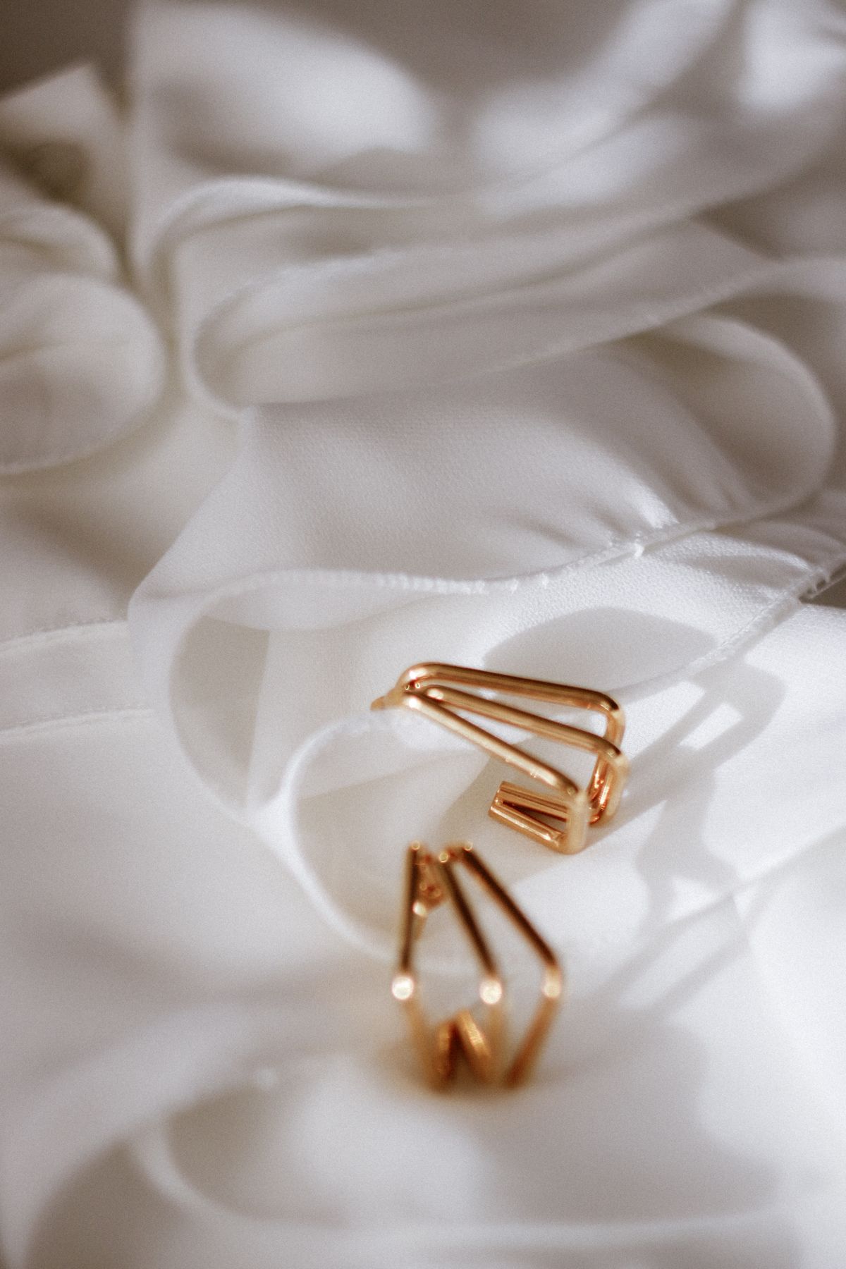 Cast metal earrings resting on white cloth