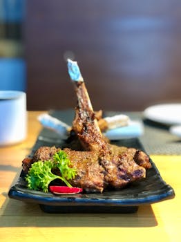 Delicious grilled lamb chops served with fresh garnishes on a black plate.