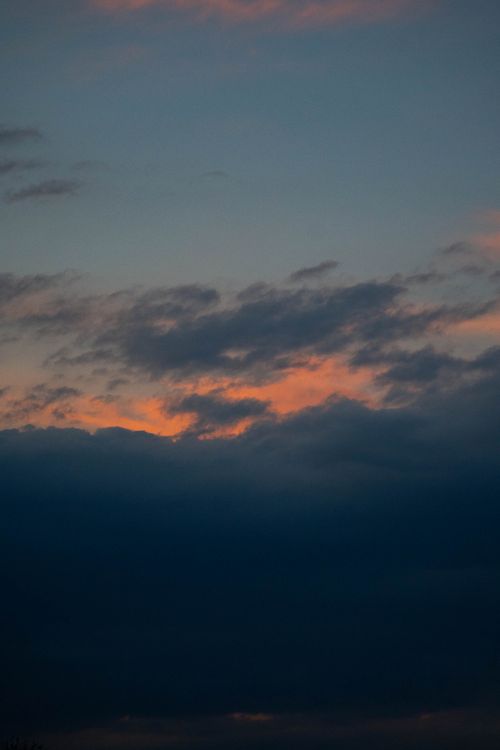 Free Captivating sunset with vibrant orange hues and dark silhouetted clouds. Stock Photo