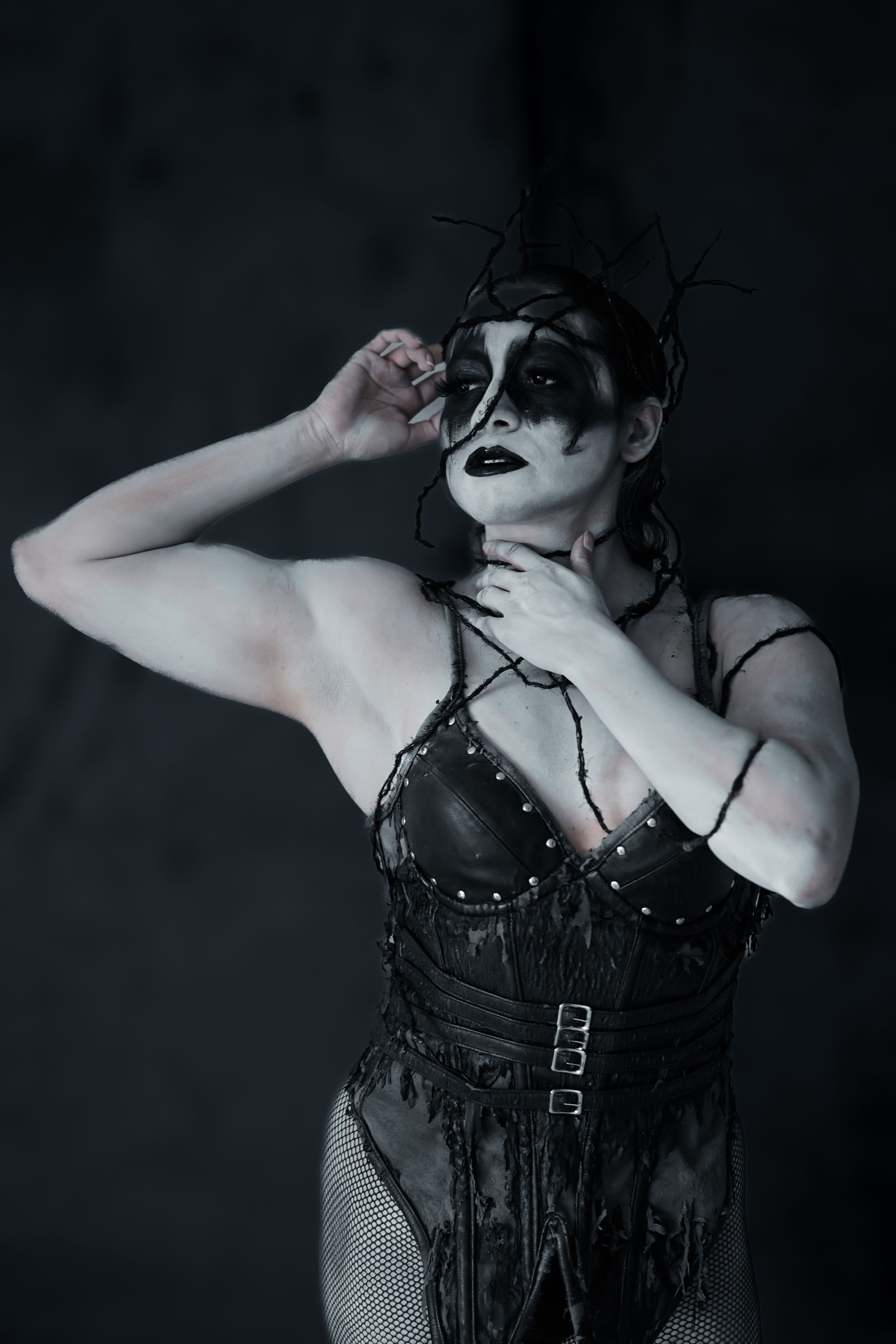 Artistic portrait of a woman with gothic face paint and intricate costume, embodying a dark theme.