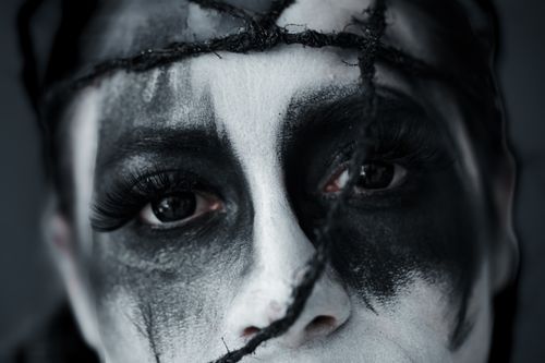 Free Close-up of a person's face with dramatic black and white paint and wrapped twine. Stock Photo