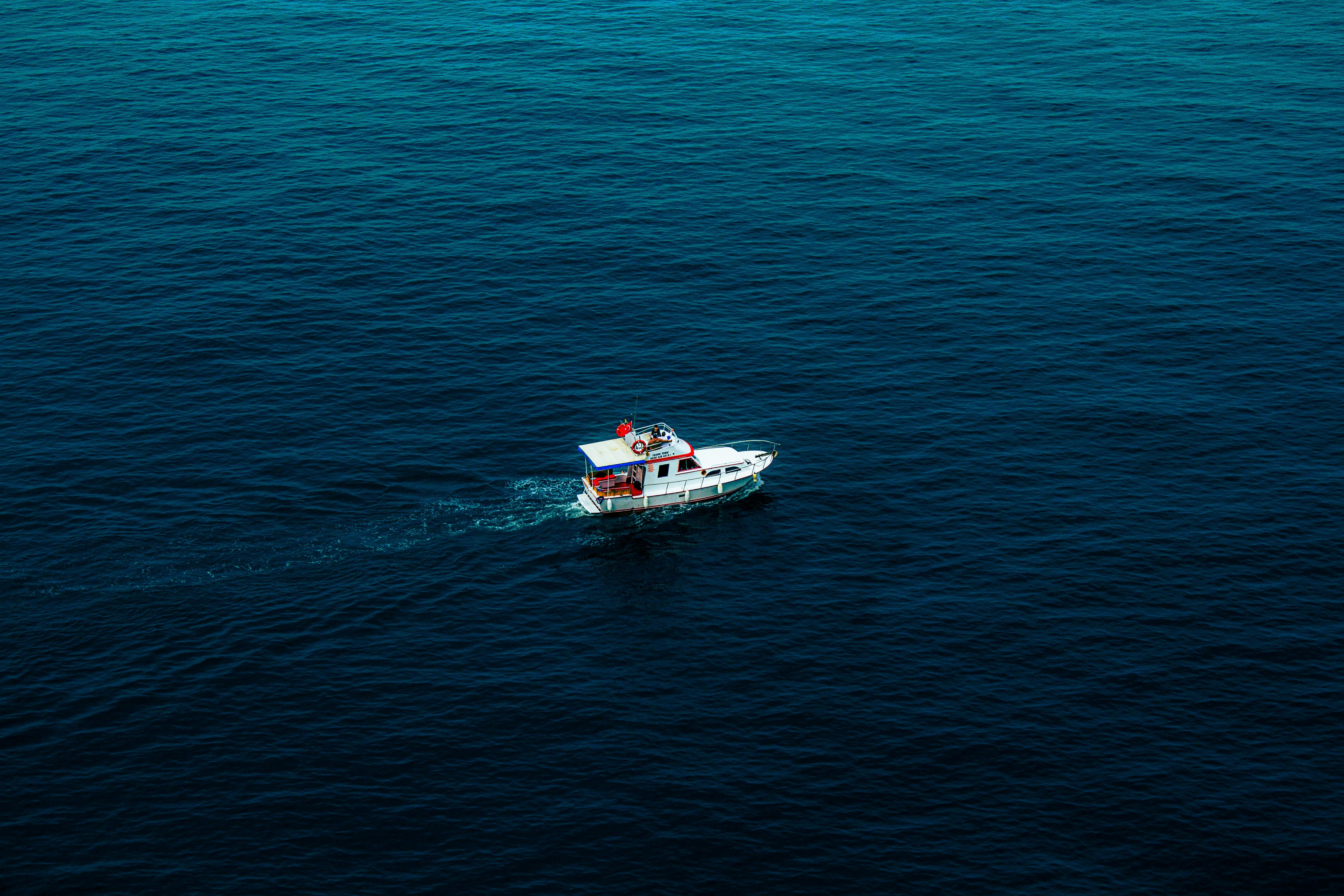 Captivating aerial shot of a boat sailing on the deep blue waters near Amasra, Bartın, Türkiye.