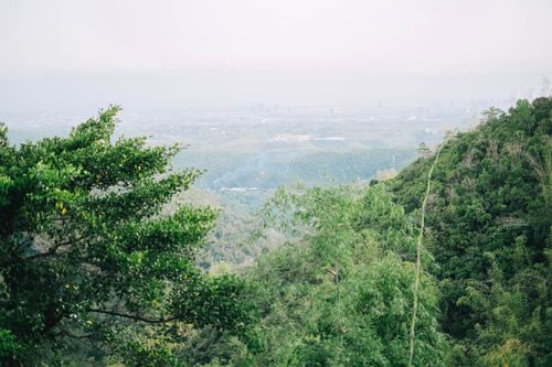 Free Expansive view of lush green mountains against a distant cityscape horizon. Stock Photo