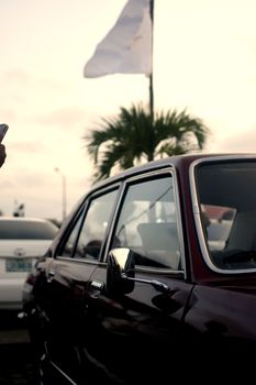 A classic vintage car parked outdoors with a palm tree in the background, captured at sunset.