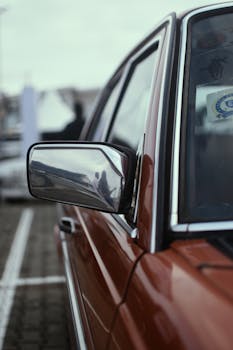 Close-up of a vintage car's side mirror reflecting its surroundings. Perfect for auto enthusiasts.