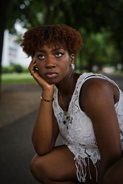 Free Captivating portrait of a woman sitting lost in thought in a Berlin park, captured in natural light. Stock Photo