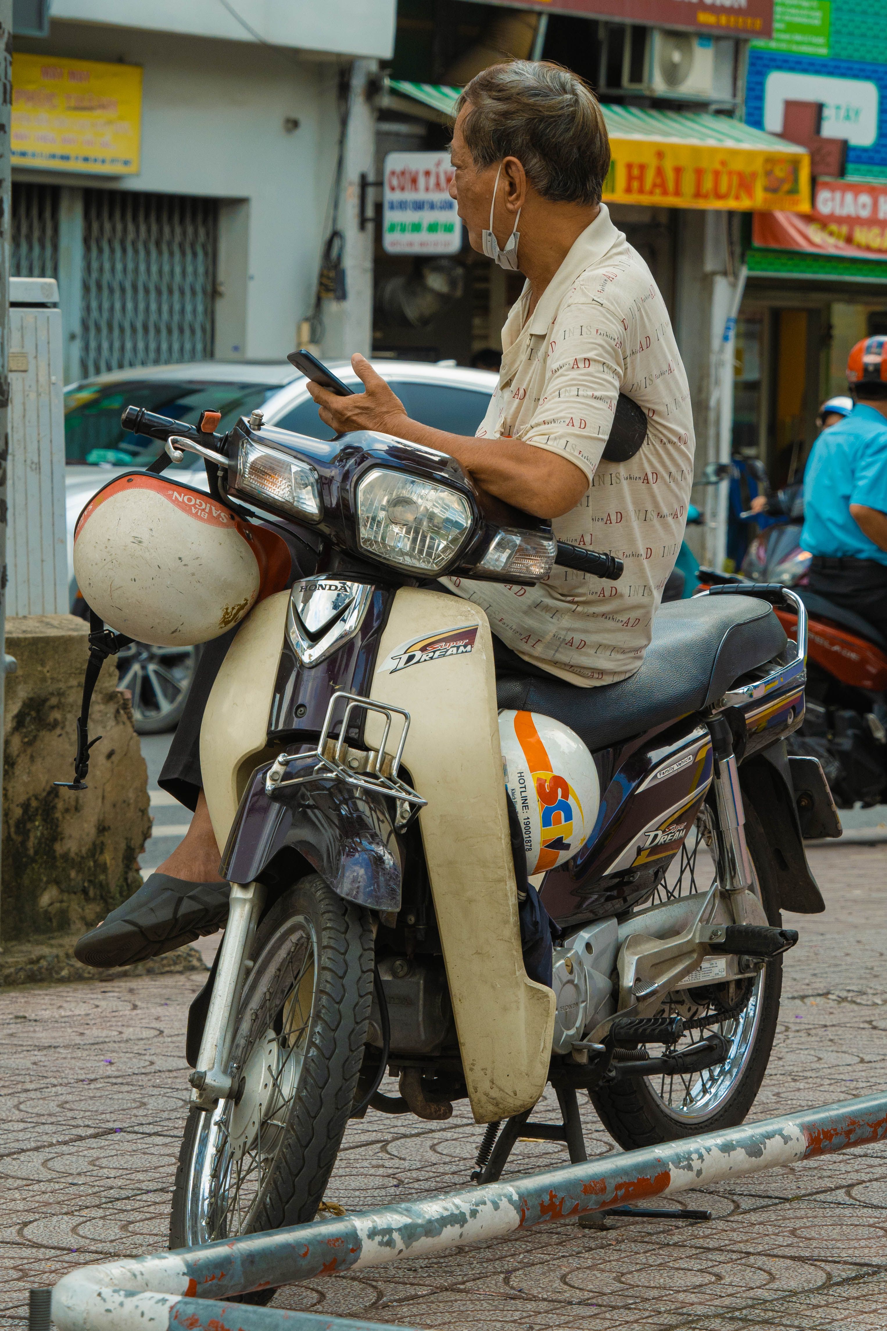 Hombre revisando el móvil sobre su moto en una calle de Vietnam