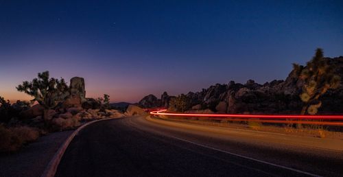 Free Stunning long exposure of a desert road at dusk with red light trails. Stock Photo