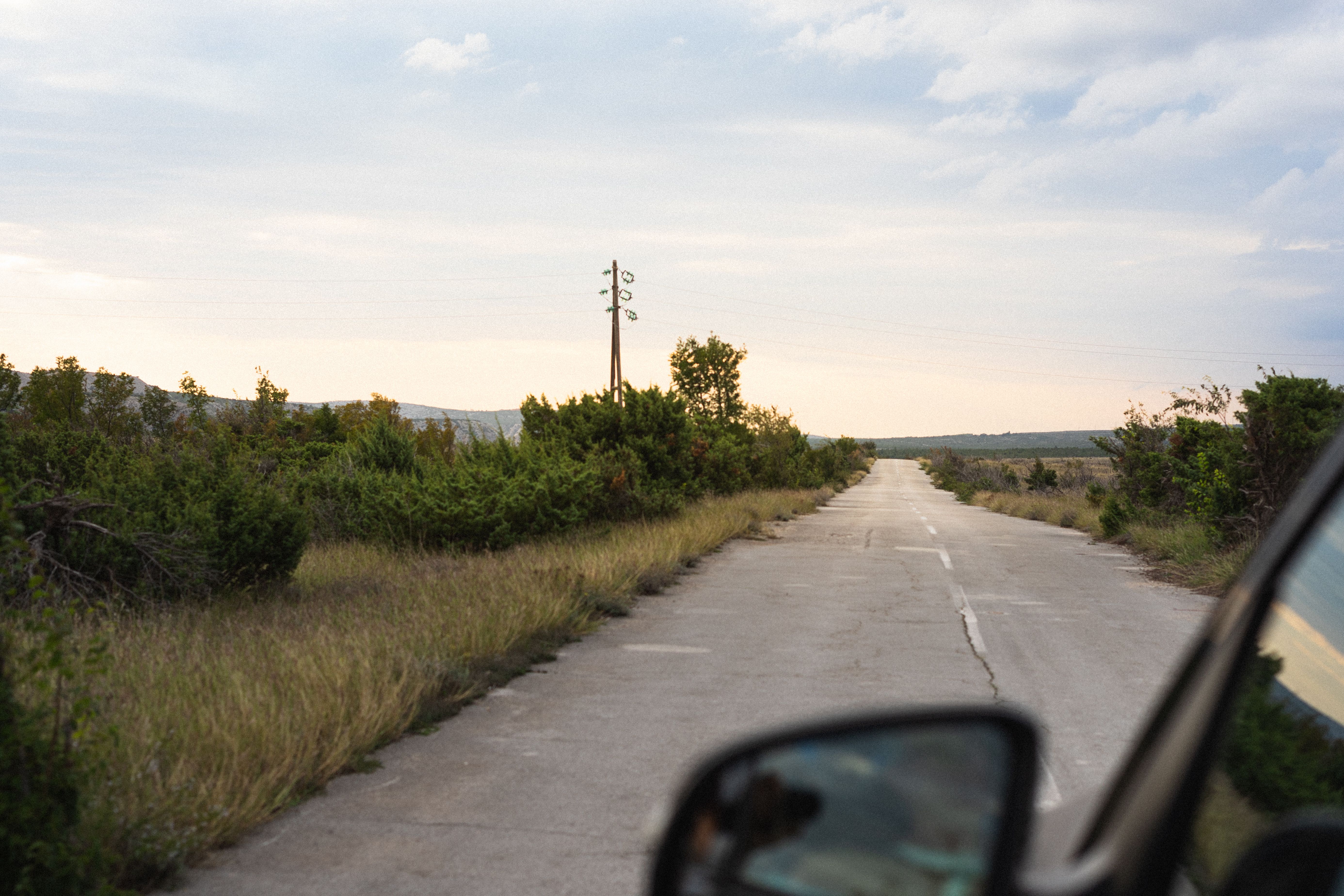 Serene drive down a secluded rural road at dusk with lush greenery surroundings.