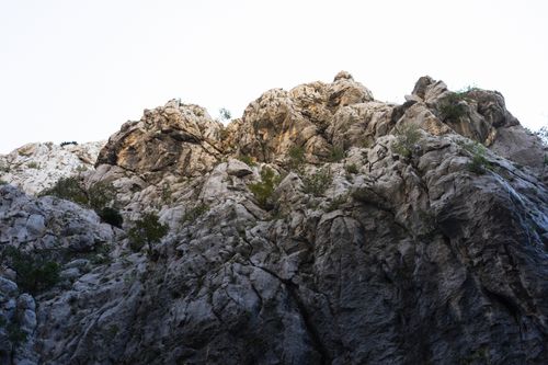 Free A rugged rocky cliff reaching towards a clear sky, showcasing nature's raw beauty. Stock Photo