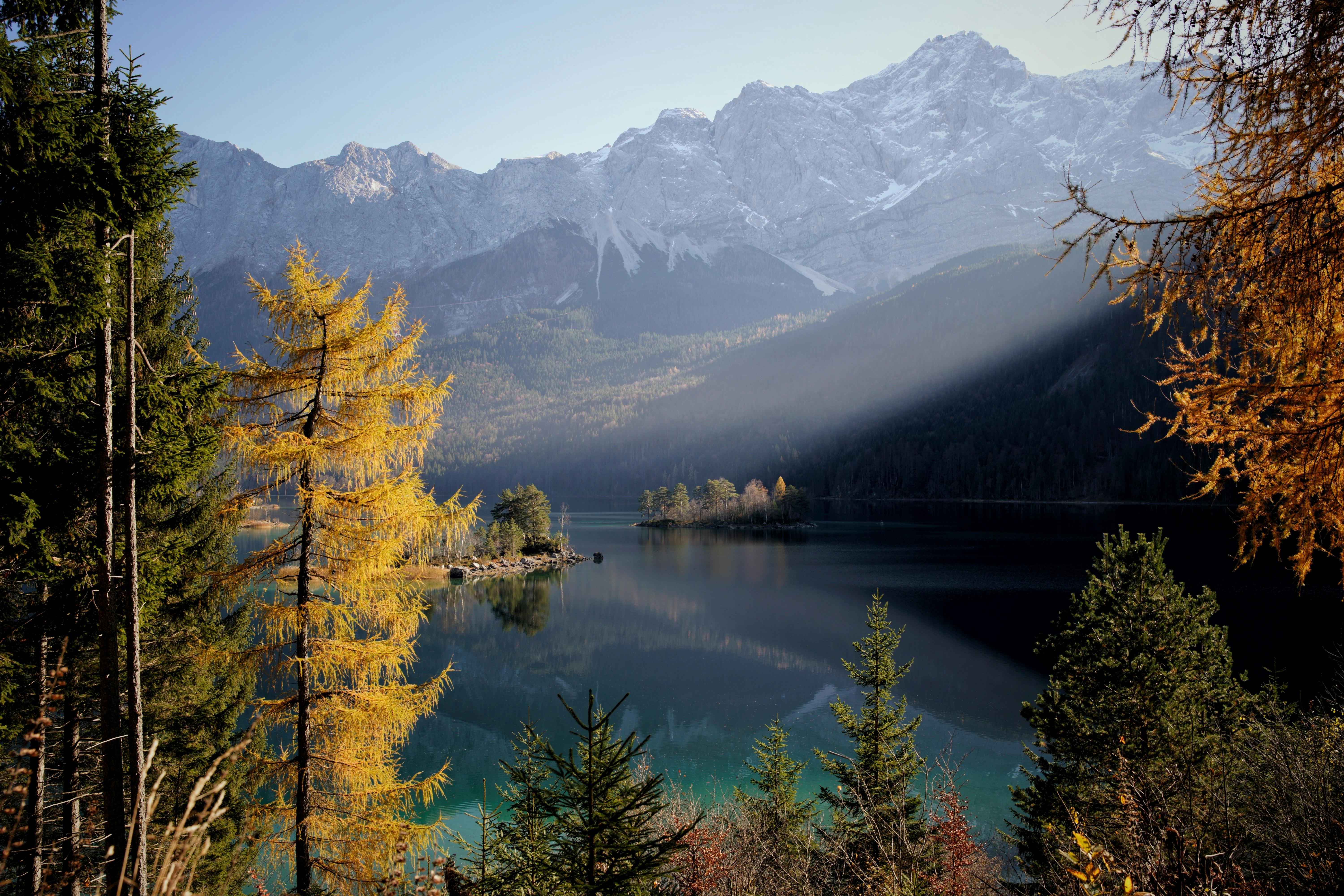 Stunning autumn landscape at Eibsee with clear waters and Zugspitze mountain backdrop.
