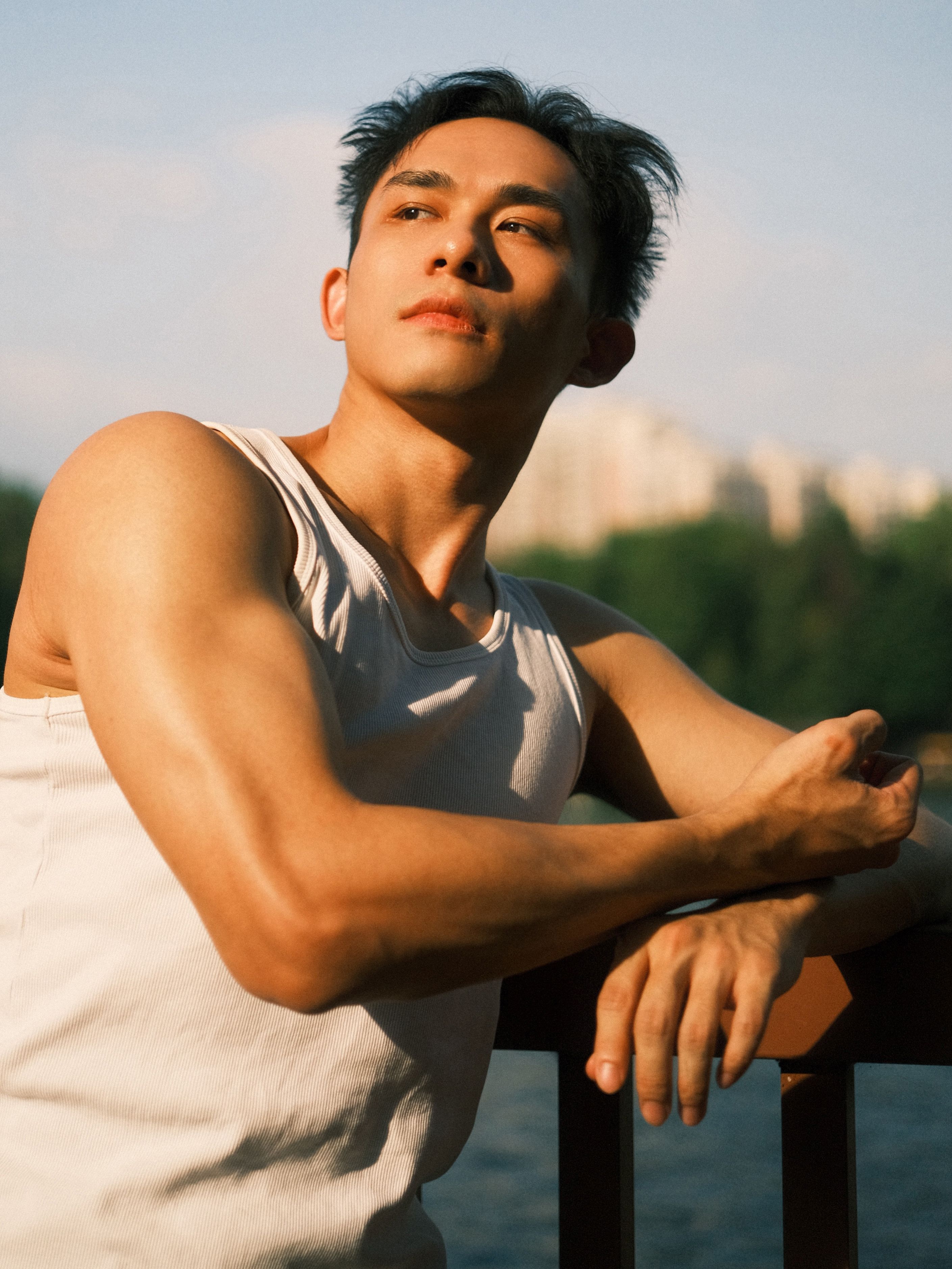 Young man in white tank top enjoying sunny day outdoors.