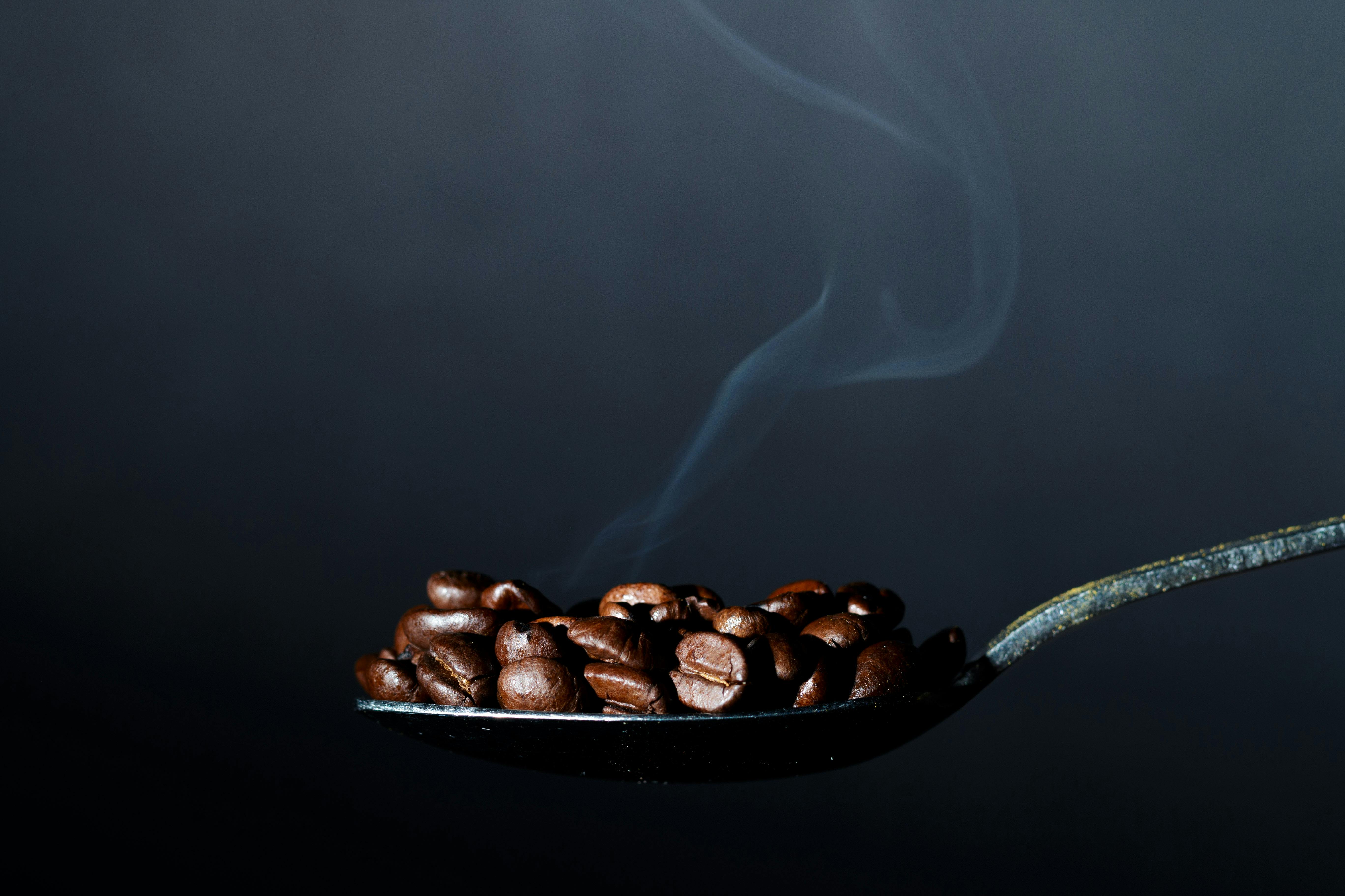 Steaming coffee beans on a spoon, suggesting caffeine dose awareness