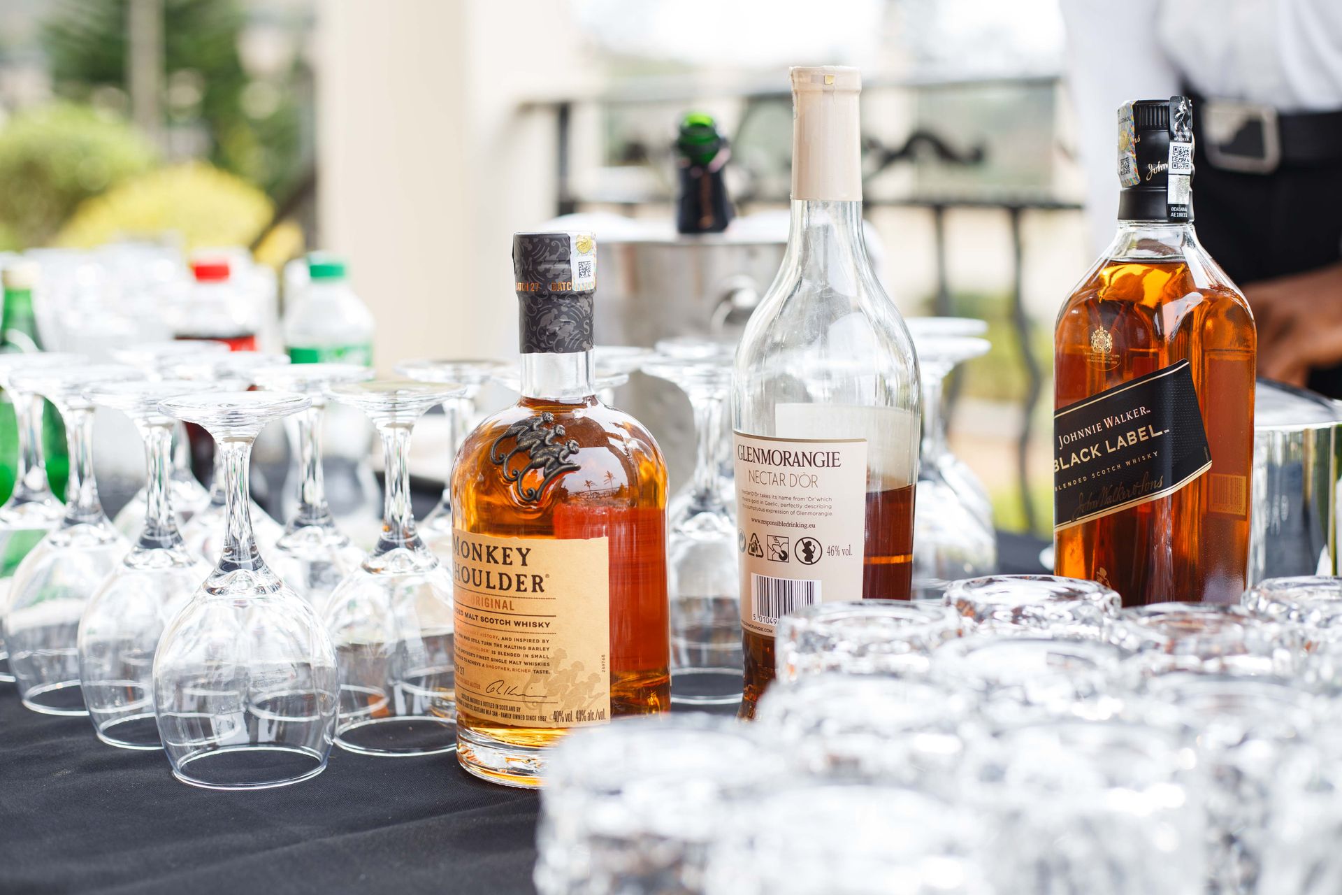 Whiskey Bottles Display with Empty Glasses Outdoors