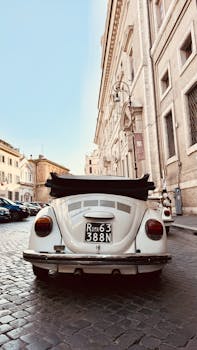 Vintage car in Rome's cobblestone street, capturing classic architecture.