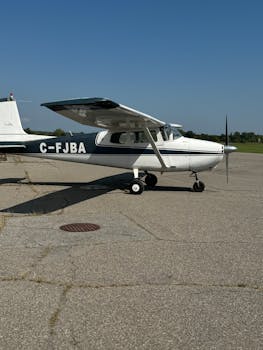 A small single-engine airplane parked on a sunny runway, ready for flight.