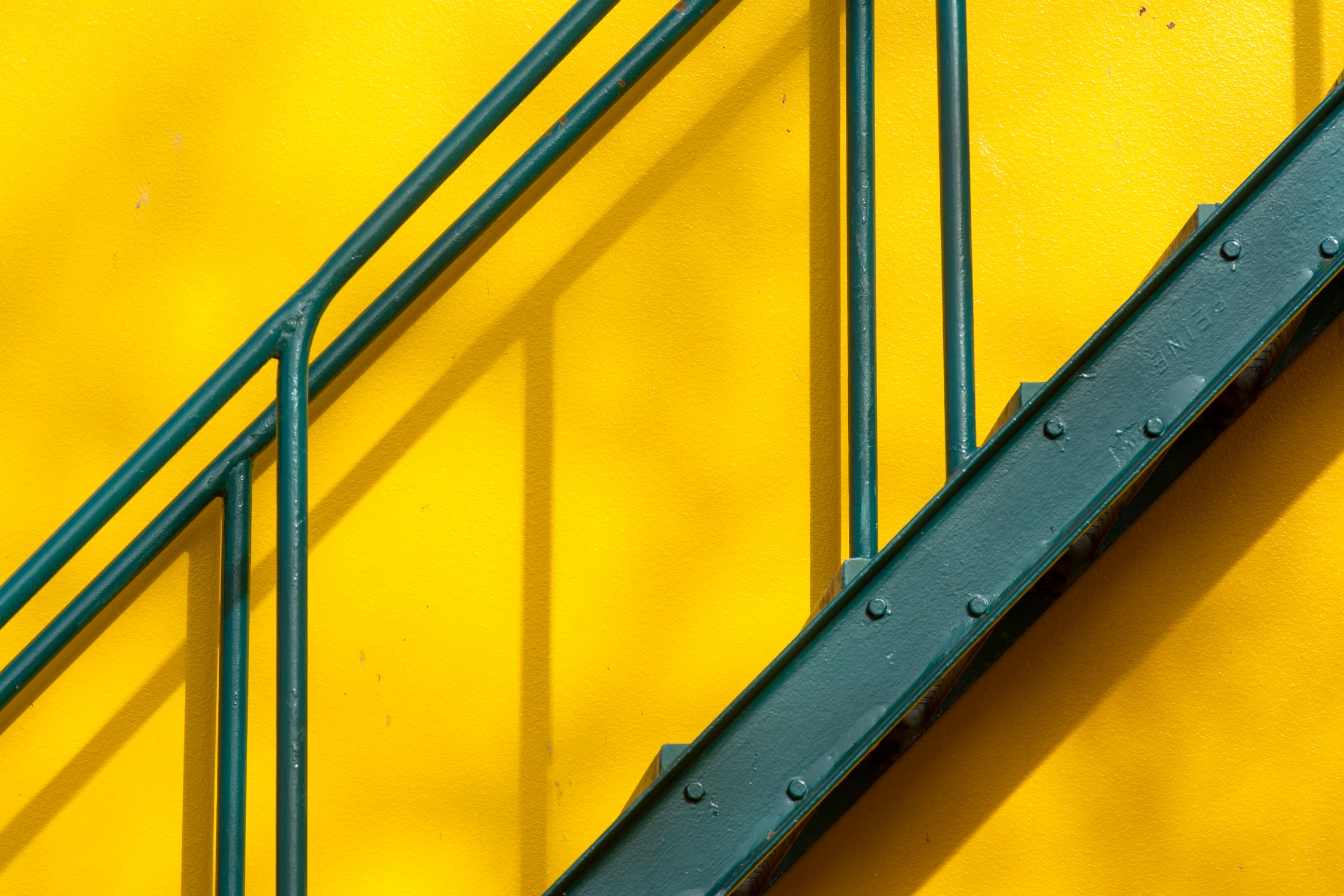 Vibrant Yellow Wall with Green Metal Railing · Free Stock Photo