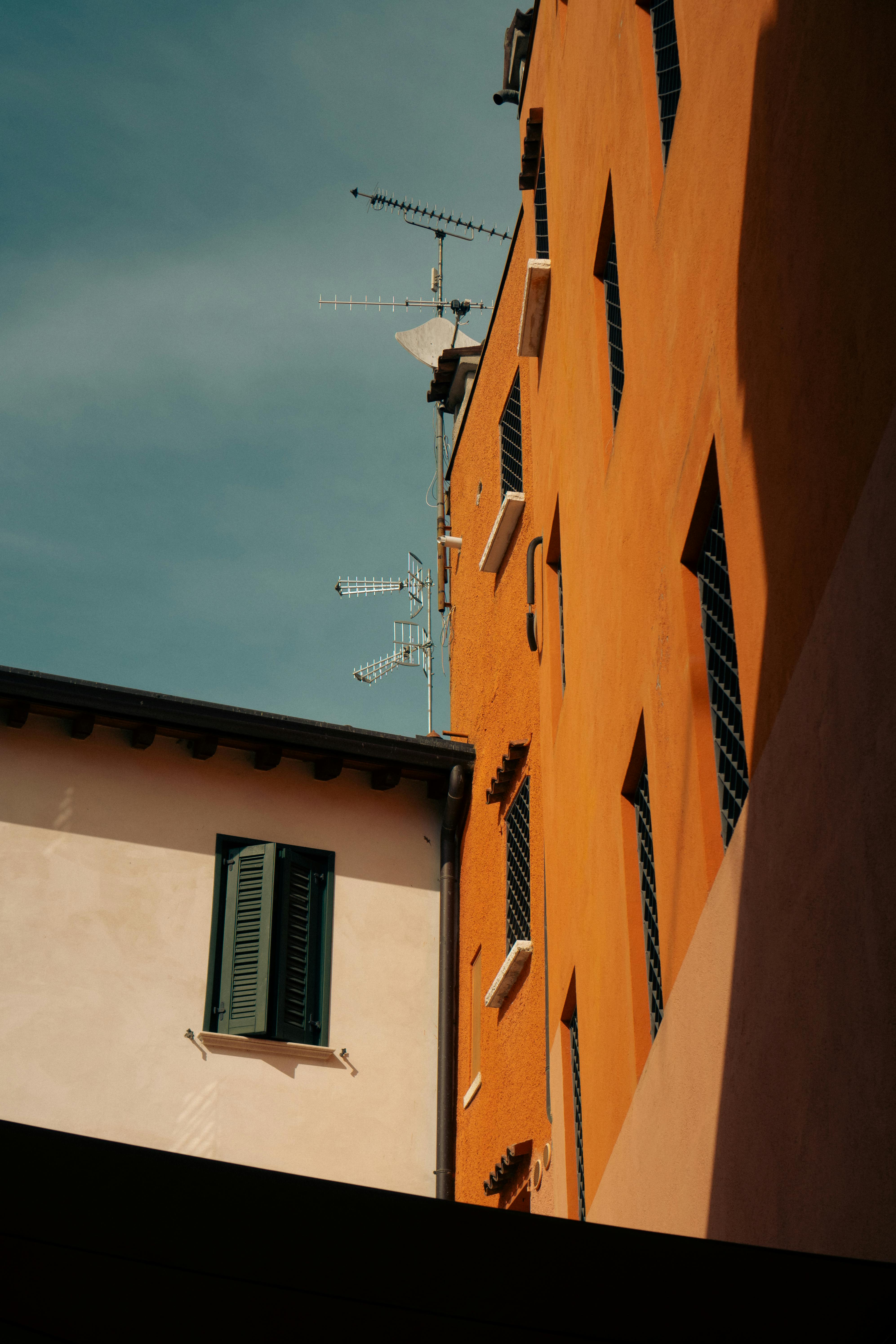 A view of urban buildings with TV antennas against a clear blue sky, showcasing architectural contrasts.