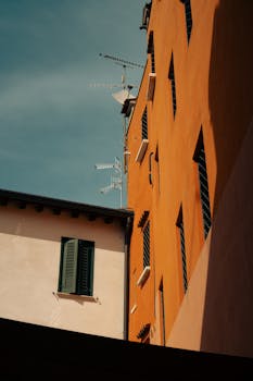 A view of urban buildings with TV antennas against a clear blue sky, showcasing architectural contrasts.