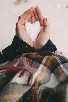 特写镜头中，手握着心形雪片，裹着冬衣