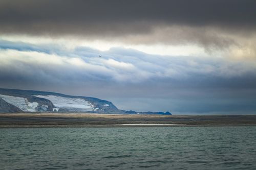 Free Moody arctic scene with glacier, ocean, and dramatic clouds. Perfect for nature and travel themes. Stock Photo