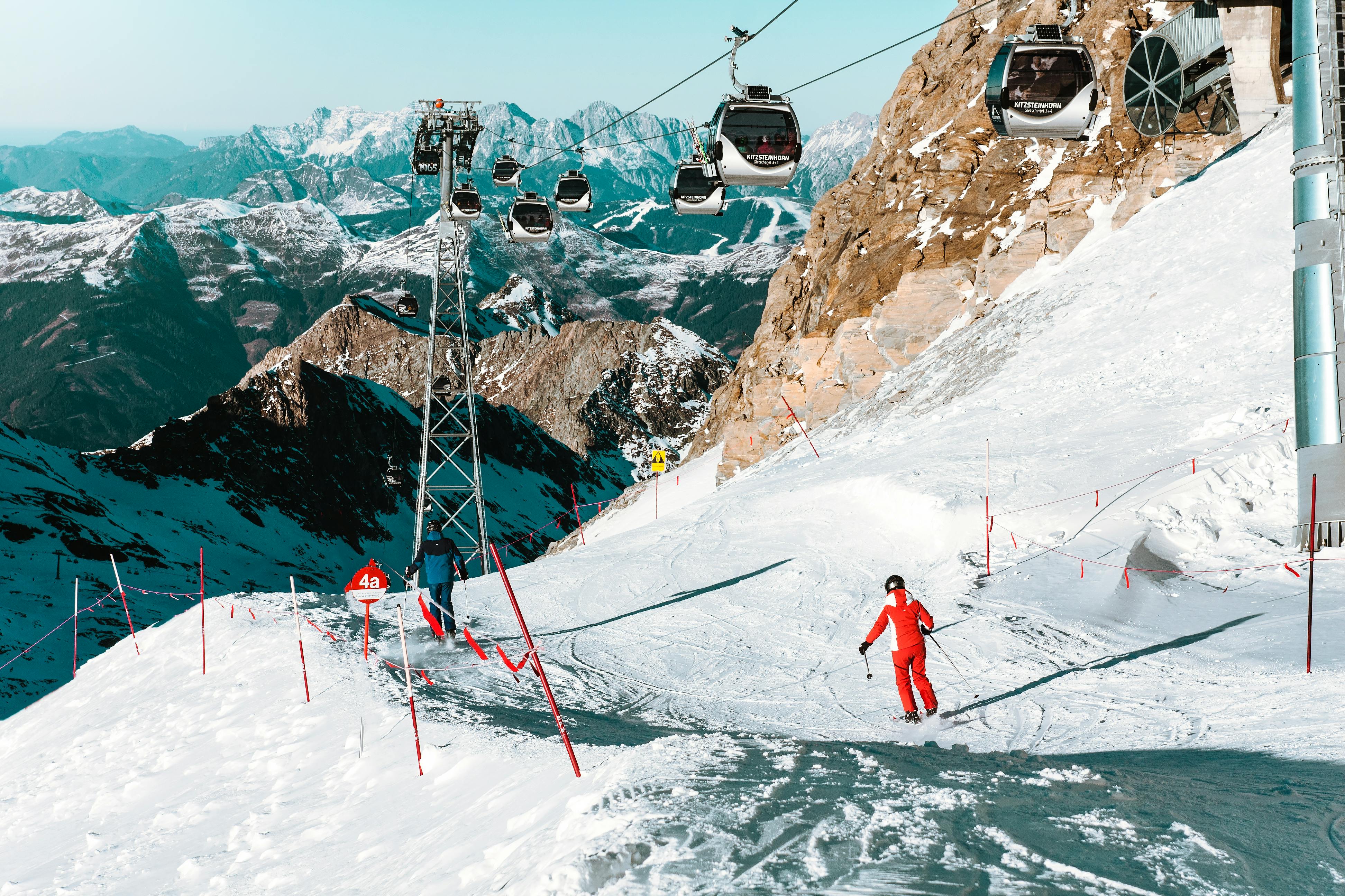 Prescription Goggle Inserts - A skier descends a snowy slope at Zell am See with cable cars and majestic mountains in the background.