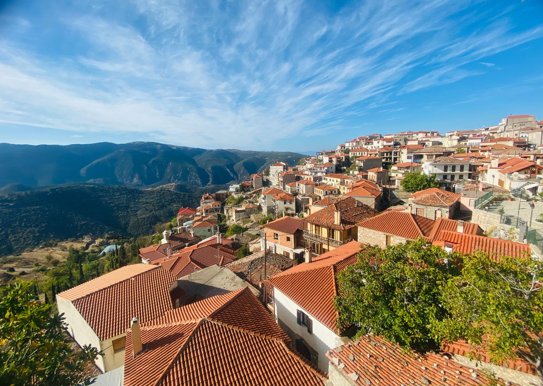 Stone houses of Arachova climbing a steep hillside below the snow-capped Parnassos mountains.