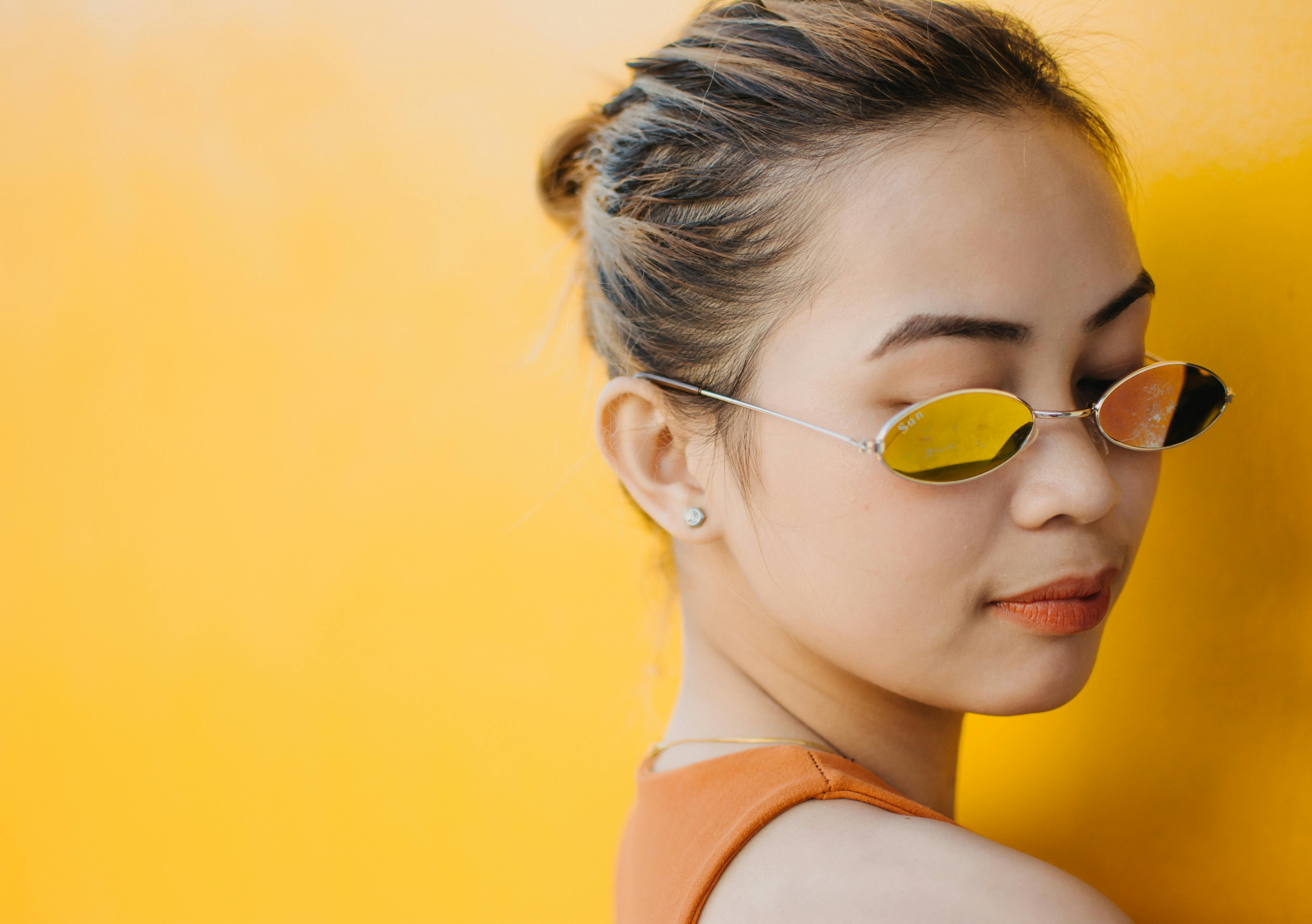 一位时尚女性戴着太阳镜，背景是充满活力的黄色