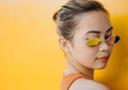 一位时尚女性戴着太阳镜，背景是充满活力的黄色