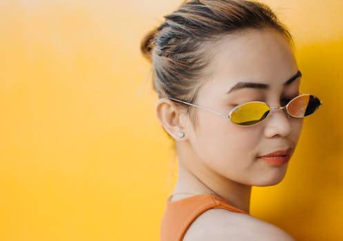 一位时尚女性戴着太阳镜，背景是充满活力的黄色