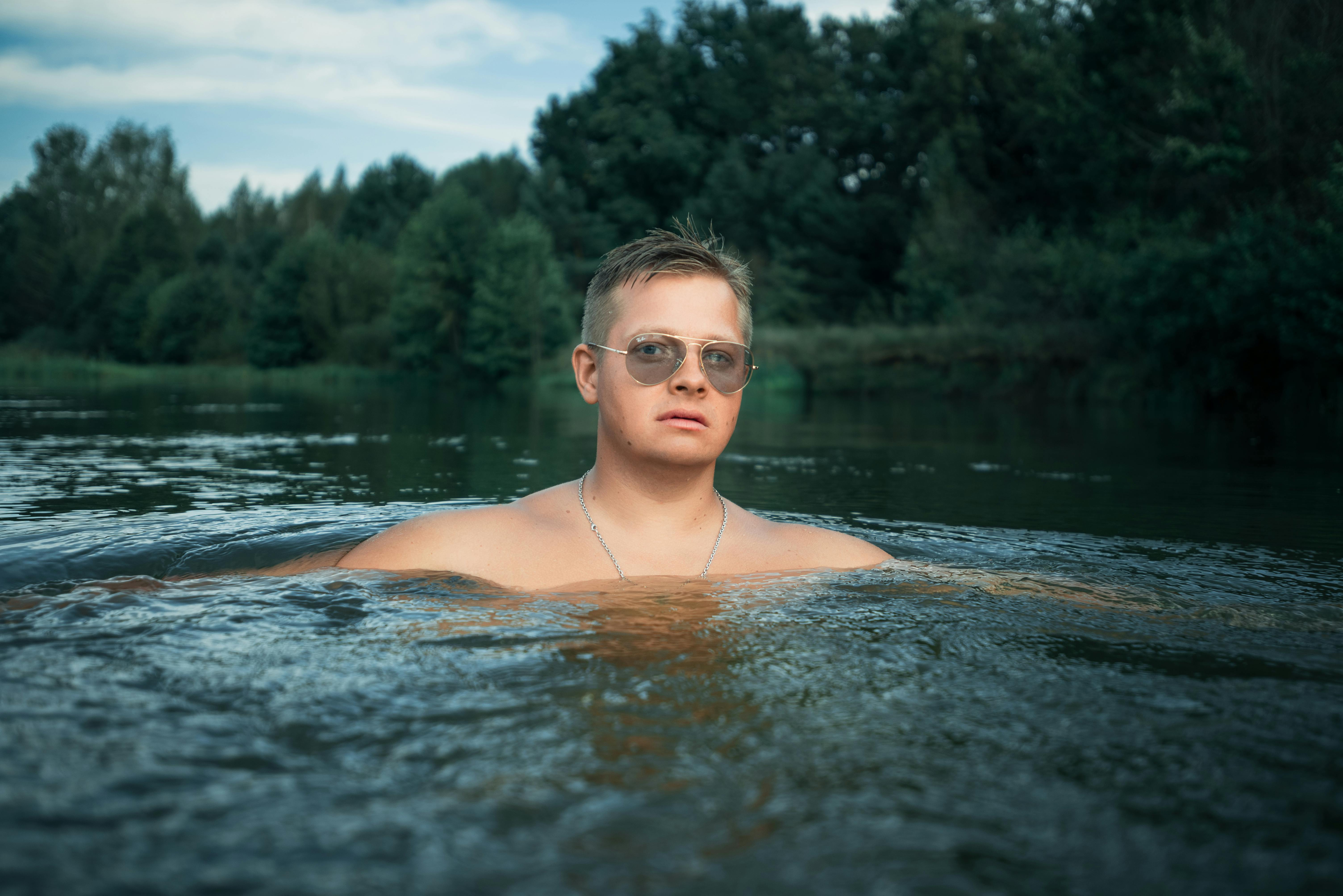 portrait of man in sunglasses in tranquil river