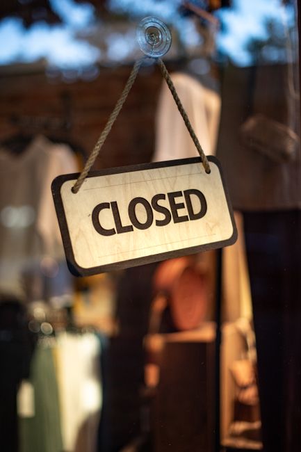 Photo by Tim Mossholder A wooden closed sign hanging on a storefront window at night.