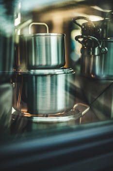 Array of shiny stainless steel pots stacked in a kitchen setting.