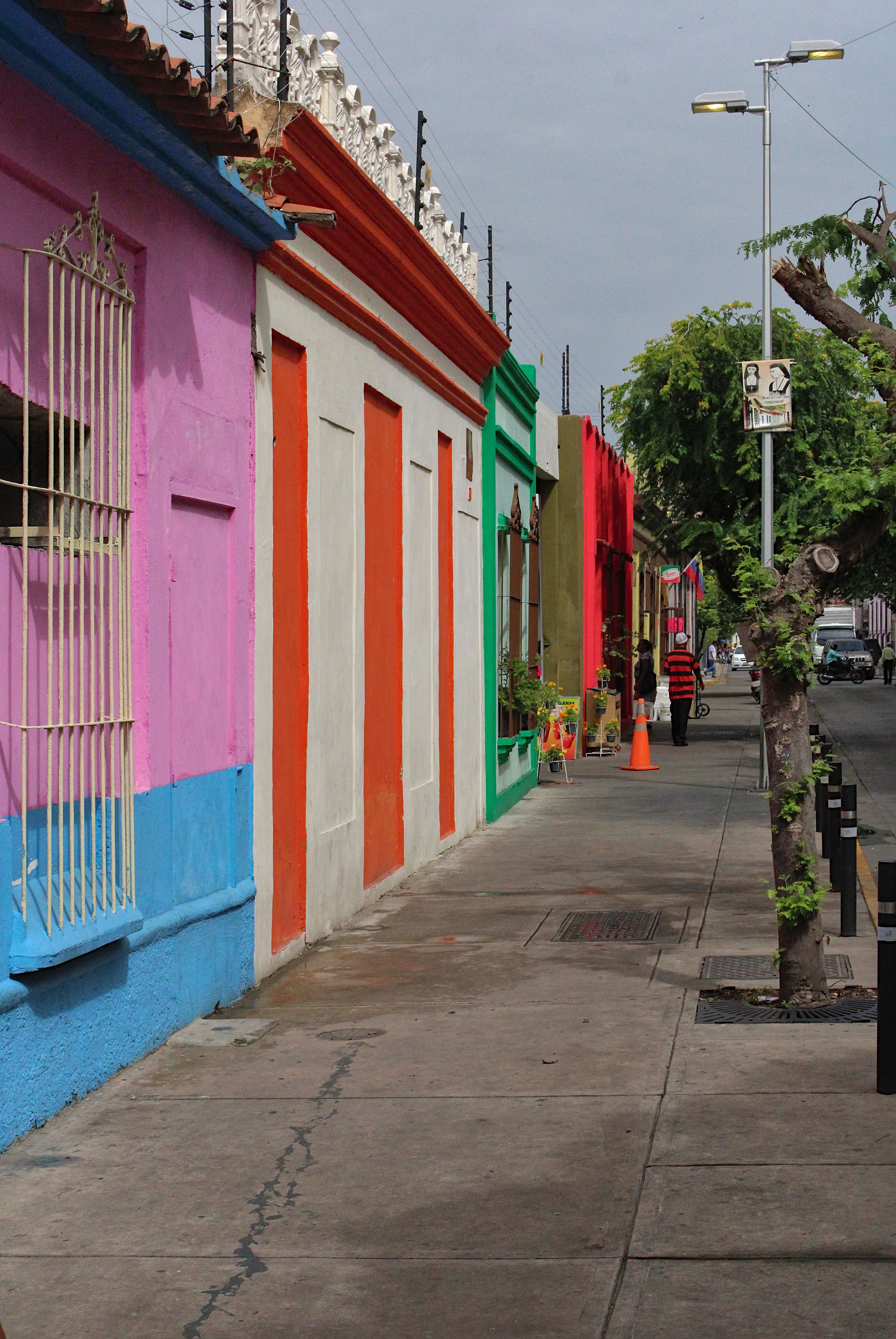 Fotomural Edificios vibrantes de colores linean una calle urbana vacía, mostrando una arquitectura diversa.