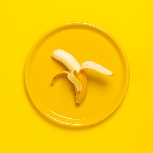Photo of Peeled Banana on Yellow Plate and Background