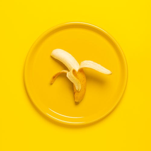 Photo De Banane Pelée Sur Plaque Jaune Et Fond