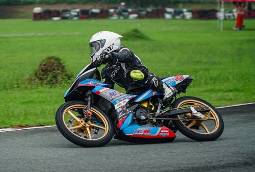Free Motorcycle racer in full gear leaning on track curve at speed, showcasing dynamic motion and skill. Stock Photo